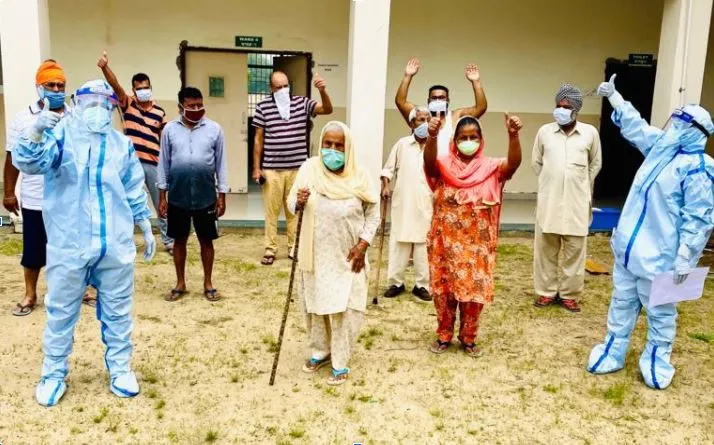 Patients in masks and healthcare workers in PPE stand at a hospital entrance in Punjab 