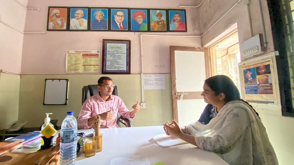 A man and woman sitting in an office and talking to each other. 