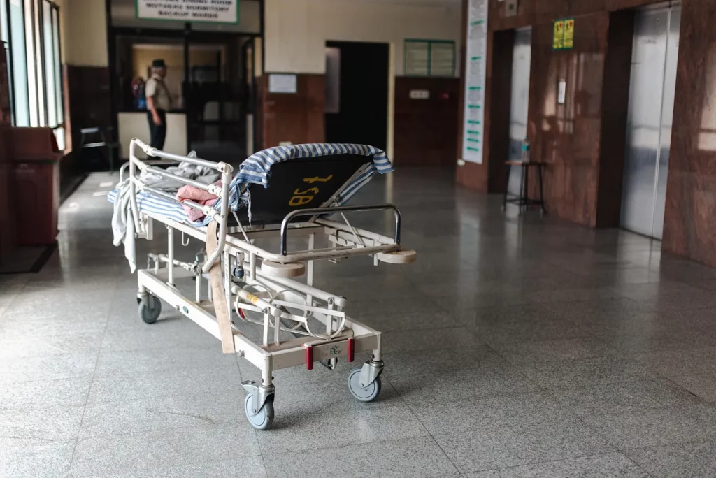 An empty hospital bed is parked in a corridor. 