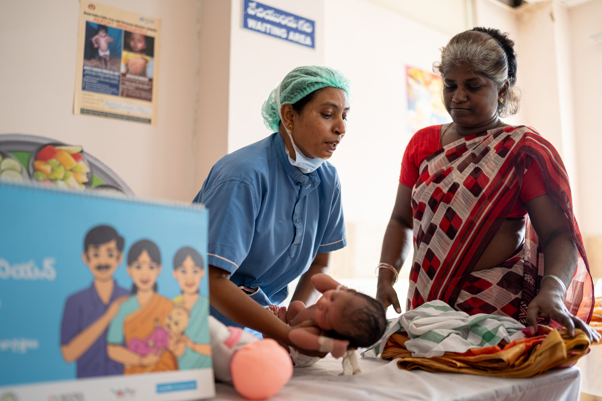 A nurse holds a baby as their caregiver looks on during a Care Companion Program session at the Government General Hospital Vijayawada, Andhra Pradesh.