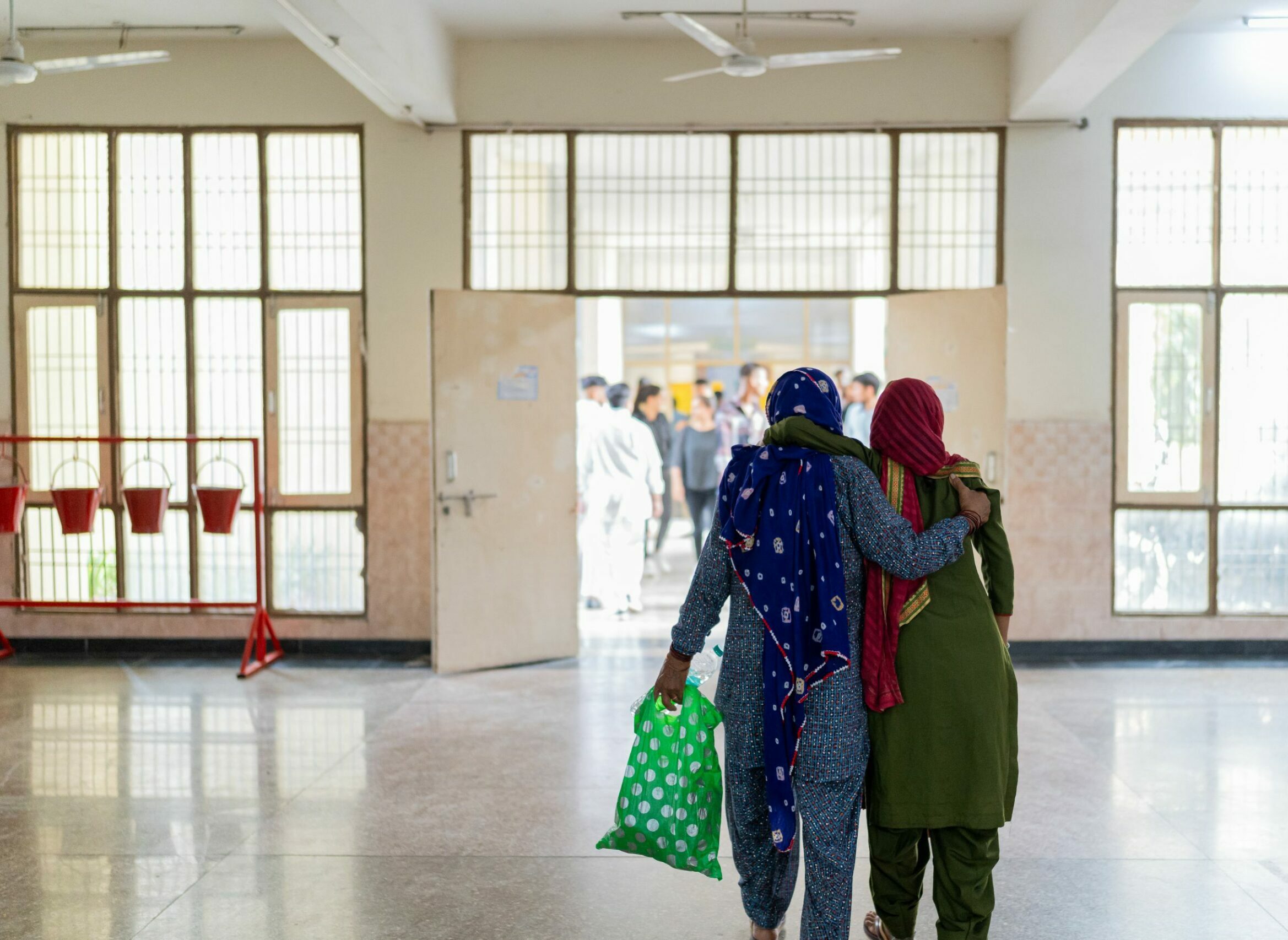 A caregiver supports a patient as they leave a hospital in Haryana, India