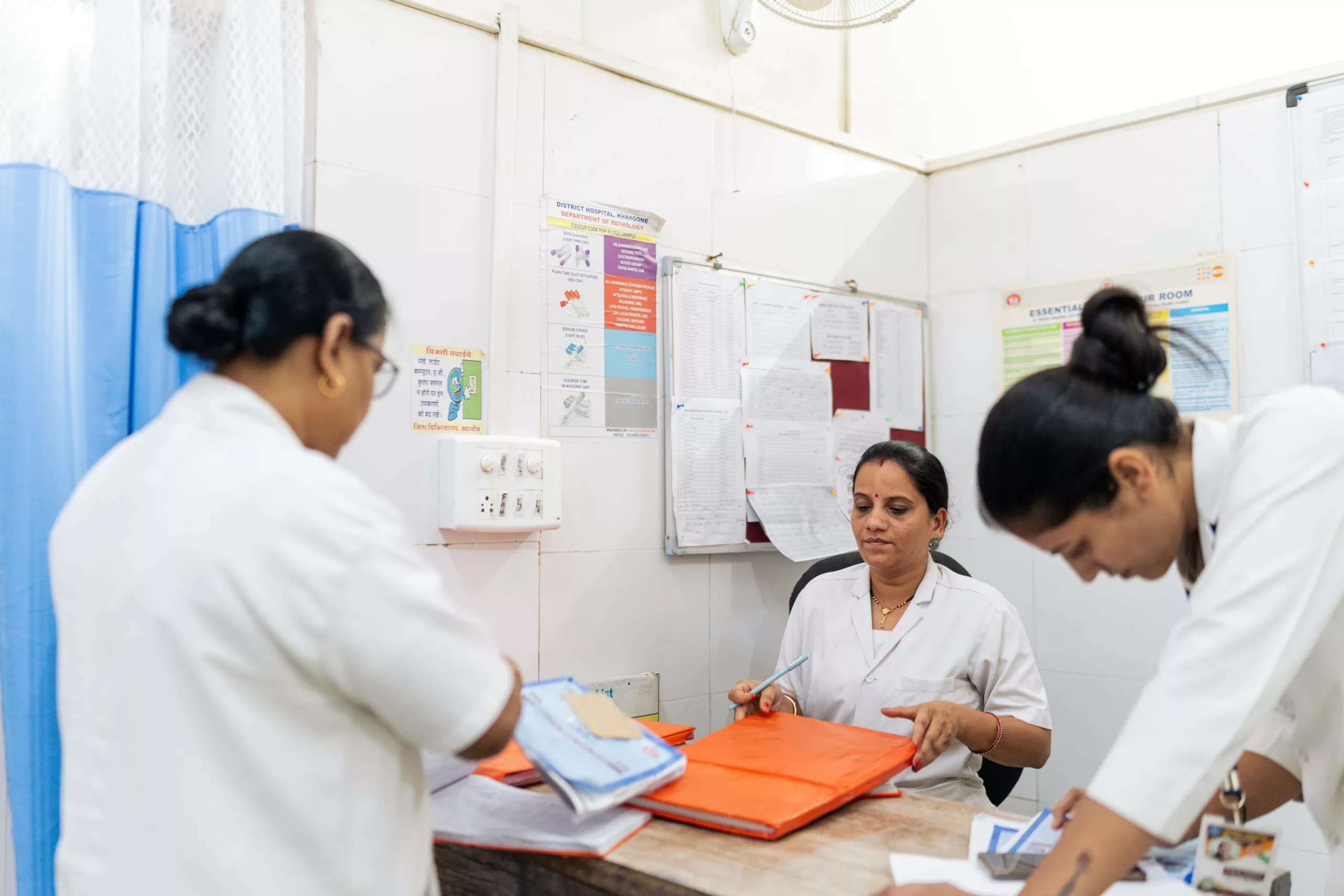 Three nurses handling documentation at a desk at the Khargone District Hospital in Madhya Pradesh, India.