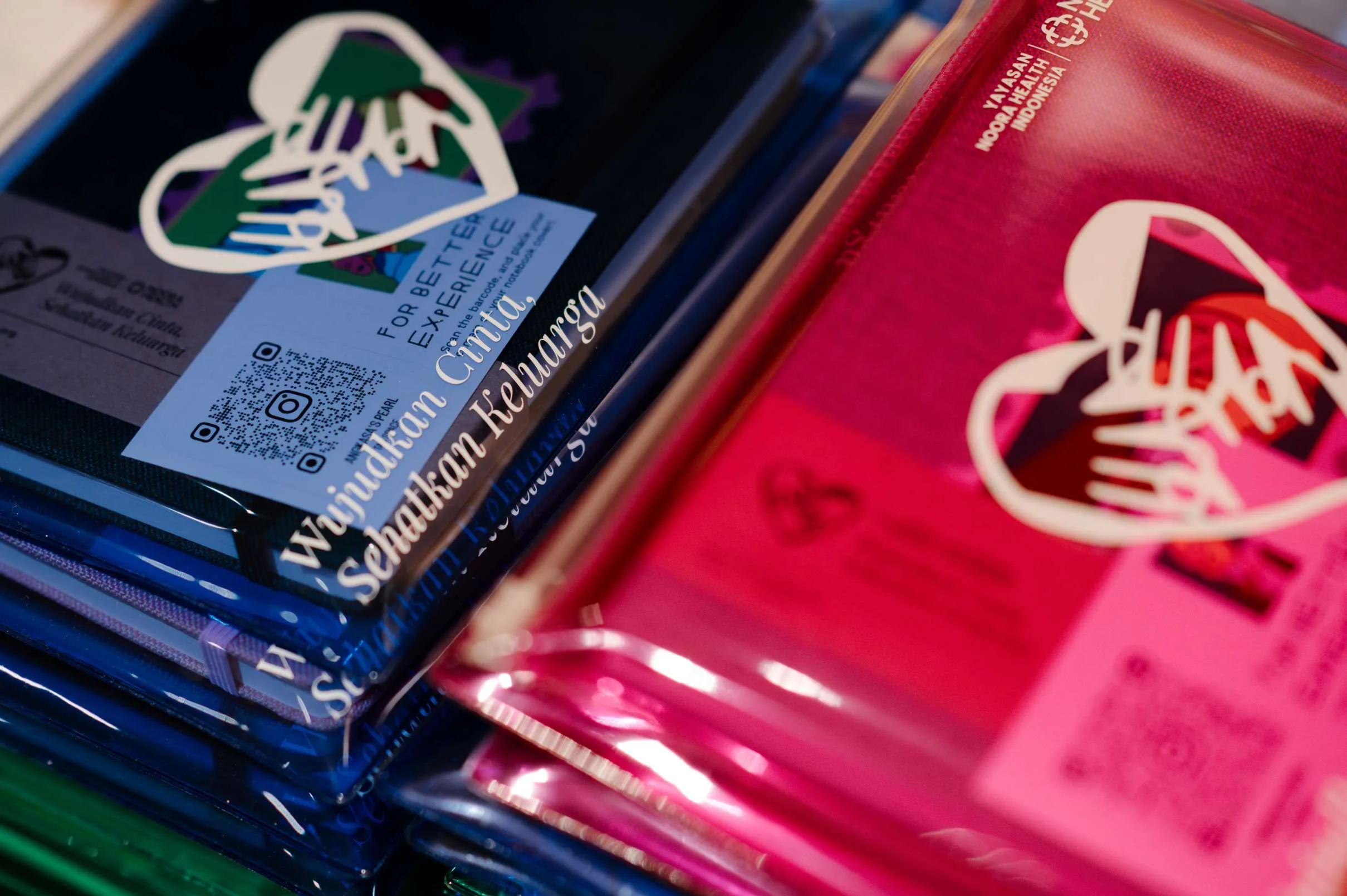 A close up of the token of appreciation created for the event, showing two transparent, blue and pink folders, with a logo.