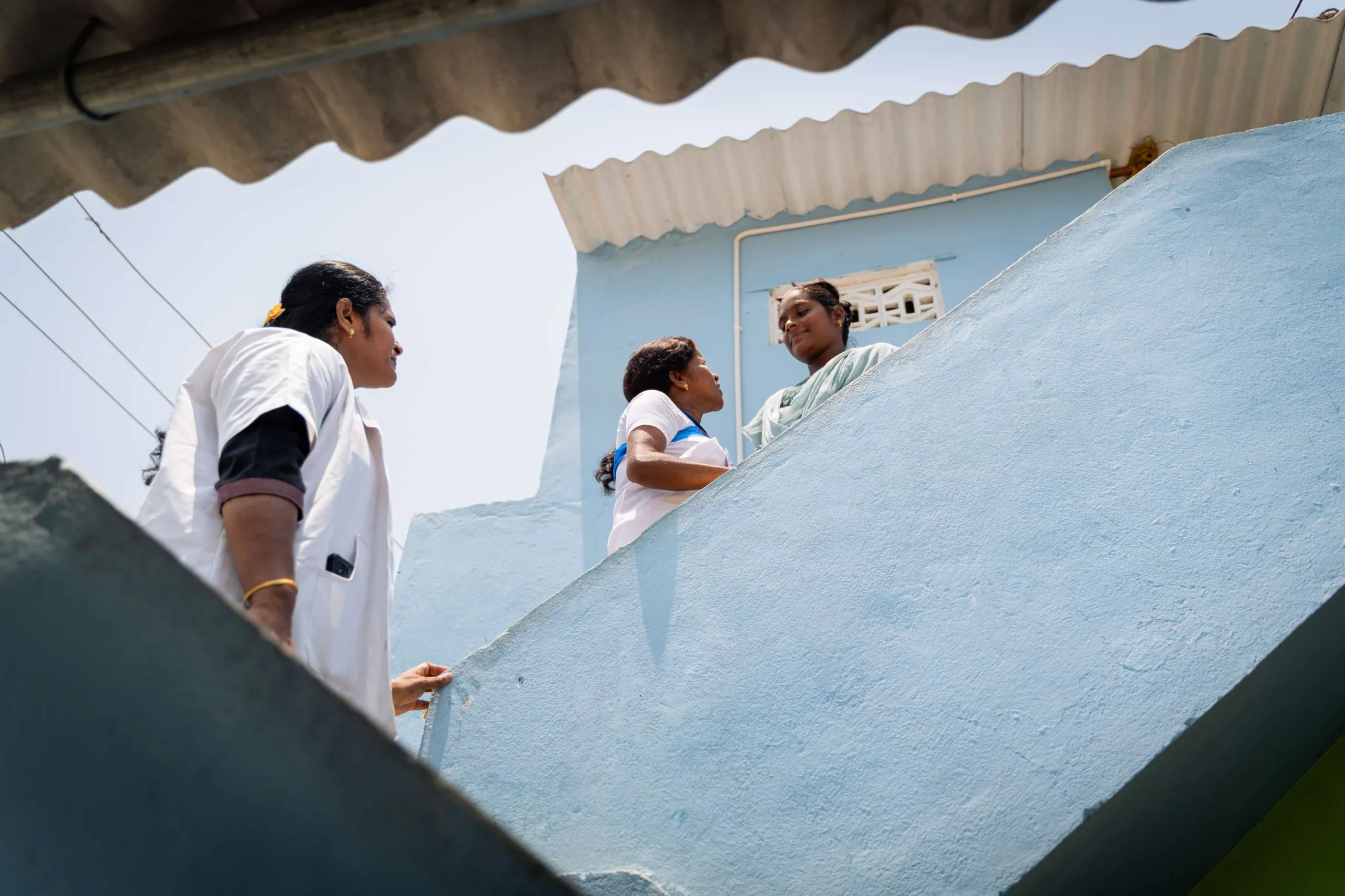 During a home visit, Santhi and an ASHA worker connect with a woman at her doorstep, offering support and guidance.